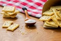 Crispy salted crackers, wooden spoon with salt crystalls, paper bag full of crackers on a red napkin on wooden table. Royalty Free Stock Photo