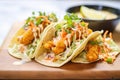 crispy shrimp tacos with spicy mayo and shredded lettuce on a tray