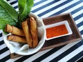 Crispy spring roll with fresh vegetable and sweet chili sauce on wooden tray