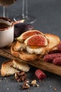 Crispy toasts with figs and honey close-up on a wooden board. Food for a romantic date on a dark stone background. Top view, dark Royalty Free Stock Photo
