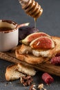Crispy toasts with figs and honey close-up on a wooden board. Food for a romantic date on a dark stone background. Top view, dark Royalty Free Stock Photo