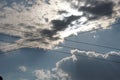 Crisscrossing power lines against a dramatic cloudy sky with bright sunlight peeking through. Royalty Free Stock Photo