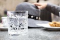 Cristal transparent glass with engraved ornament. Grey hat coffee cup and pastry in background out of focus. Artistic Royalty Free Stock Photo