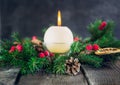 Cristmas card with focused fir cone and branches of advent wreath with natural decor and blurred burning candle on the old rustic