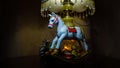 Cristmas presents. A toy, a white rocking horse, small gifts, a green ball, a pine cone. Night light. Zone light on gold fabric.