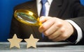 A critic holds a magnifying glass over two stars. Rating, feedback and review of a restaurant or hotel. Quality of service.