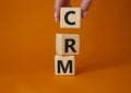 CRM - Customer relationship management symbol. Concept word CRM on wooden cubes. Businessman hand. Beautiful orange background. Royalty Free Stock Photo