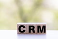 CRM Customer Relationship Marketing written on a wooden cube in front of a laptop