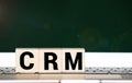 CRM Customer Relationship Marketing written on a wooden cube in front of a laptop