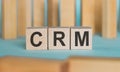 CRM Customer Relationship Marketing written on a wooden cubeon a blue table with wooden background.. Business concept