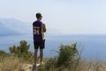 Croatia, August 3 2017, Young man standing in shorts, t-shirt and sunglasses looking out the ocean Royalty Free Stock Photo