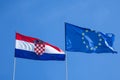 Croatian and European flags waiving in the air with a blue sky background. Croatia is the youngest country that joined the EU