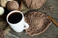 Crochet from brown yarn crochet with a wooden handle. Knitting over an old wooden table. Favorite hobby for a cup of coffee
