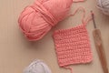 Crochet handmade square pattern, pink yarn coil, hook, knitting crocheting top view on a wooden background