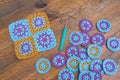 Crochet patterns in turosque, lilac and yellow colors, crochet tricot hook and a yellow thread layed out on scratched wooden