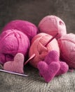 Crochet pink hearts and yarn on wooden background