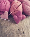 Crochet pink hearts and yarn on wooden background.