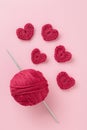 Crocheted amigurumi pink heart with crochet hook and skein of yarn on a pink background. Valentine\'s day banner