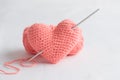 Crocheted amigurumi pink heart with crochet hook and skein of yarn on a white background. Valentine\'s day banner