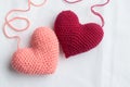 Crocheted amigurumi pink heart with crochet hook and skein of yarn on a white background. Valentine\'s day banner