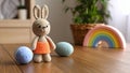 Crocheted bunny toy with Easter eggs and rainbow decor on wooden table. Royalty Free Stock Photo