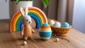 Crocheted Easter bunny, egg, rainbow, and eggs in a basket on a wooden table, holiday decor. Royalty Free Stock Photo