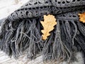 Crocheted gray shawl lying on a bench in the autumn park. Square motifs. Autumn leaves