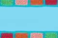 crocheted lace tablecloth of multicolored squares ornament on a blu background, top view, place for text, natural wool