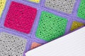 crocheted lace tablecloth of multicolored squares ornament, sheet of notebook to write to the ruler, top view,