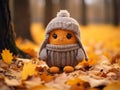 a crocheted owl wearing a winter hat sits on the ground surrounded by fallen leaves Royalty Free Stock Photo