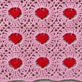 Crocheted textile featuring a grid of pink circular motifs with red heart-shaped Royalty Free Stock Photo
