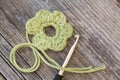 Crocheted yellow bloom with crochet hook and wool on wooden tablel Royalty Free Stock Photo