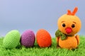Crocheted yellow chicken next to colorful Easter eggs Royalty Free Stock Photo