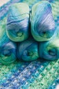 Crocheting in blue and green tones and skeins piled together