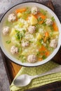 Crockpot Rice soup with meatballs, vegetables and herbs close-up in a bowl. Vertical top view