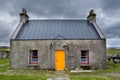 The croft house whitehouse, with orange door and dark red windows, on a stormy, cloudy day Royalty Free Stock Photo