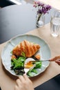 Croissant with avocado and salmon and lettuce and poached egg. A girl cuts a poached egg, the yolk oozes out