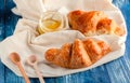 Croissant with a beautiful crisp and a jar of honey on a light fabric, delicious pastries with honey