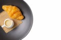Croissant on black plate with sweetened condensed milk and sackcloth isolated over white background. with clipping path. Croissant