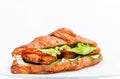 Croissant with chicken cutlet, fresh cucumber, tomato and lettuce on a white background. Royalty Free Stock Photo