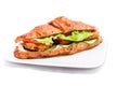 Croissant with chicken cutlet, fresh cucumber, tomato and lettuce on a white background. Royalty Free Stock Photo