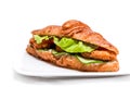 Croissant with chicken cutlet, fresh cucumber, tomato and lettuce on a white background. Royalty Free Stock Photo