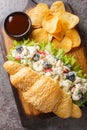 Croissant chicken salad sandwich with potato chips closeup on a wooden board. Vertical top view Royalty Free Stock Photo