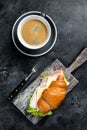 Croissant Club Sandwich with Ham and Cheese, cup of coffe. Black background. Top view Royalty Free Stock Photo