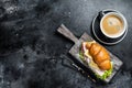 Croissant Club Sandwich with Ham and Cheese, cup of coffe. Black background. Top view. Copy space