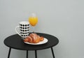 Croissant Cup with Black dots Glass of juice. black Table. morning Breakfast. Gray Background. Interior. Royalty Free Stock Photo