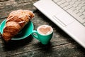 Croissant and cup of coffee with laptop Royalty Free Stock Photo