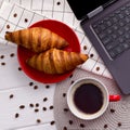 Croissant and cup of coffee with laptop on wooden table. Royalty Free Stock Photo