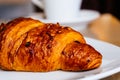 Croissant filled with chocolate and decorated with hazelnuts, at the bottom cup of hot coffee Royalty Free Stock Photo