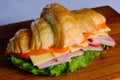 Croissant with ham and cheese isolated on a wooden background